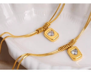 Close-up of double-layer gold snake bone necklaces with heart zircon square pendants