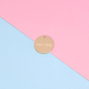 Polished golden stainless steel round pendant with for life engraving on a bicolor background