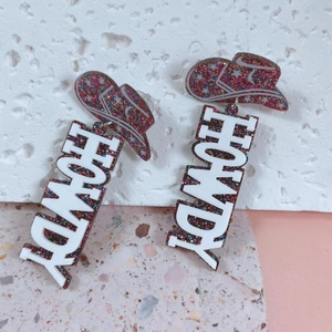 Detailed shot of glittery brown cowboy hat earrings with white HOWDY lettering charms