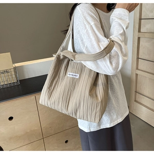 Detail der beige Falten-Tasche mit Kiss You Self Textetikett und Schultergurt-Design