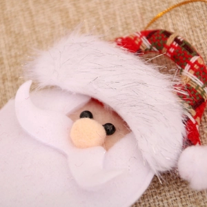 Detail of Santa Claus plush hanging ornament with a golden string on burlap background