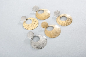 Detail of gold and silver round hoop earrings with hammered metal texture design