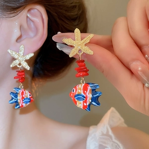 Close-up of ocean-themed starfish and colorful tropical fish drop earrings on model