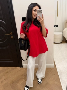 Detail of red loose-fit T-shirt paired with white wide-leg trousers and black bucket bag