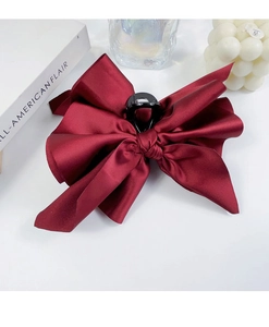 Detail of a large wine red satin bow hair claw clip with a glossy silk texture finish