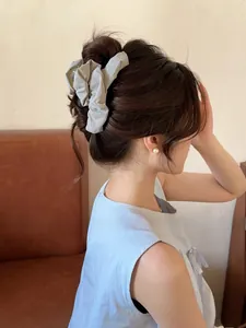 Detail of grey pleated fabric hair claw clip worn on a bun for a sweet, elegant look