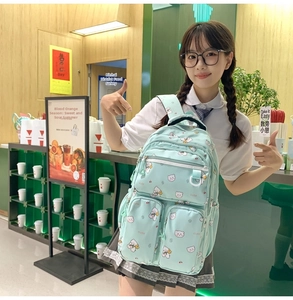 Detail of mint green school backpack with cute bear patterns and multiple zip pockets