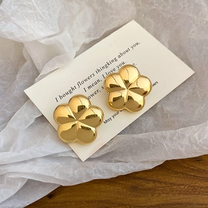 Detailed view of polished gold five-petal flower earrings on an elegant display card