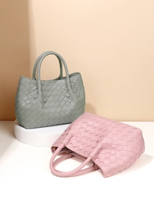 Handwoven leather bucket bags in pink and sage green colors on professional studio display