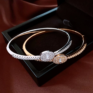 Detail of 18K gold and silver oval halo bangles set in a luxury velvet jewelry box