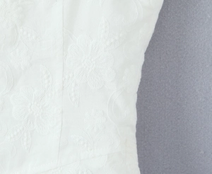 Close-up of intricate 3D floral embroidery and white fabric texture on a women camisole