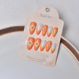 Détails de faux ongles amande faits main avec dégradé orange et reliefs de fleurs en 3D
