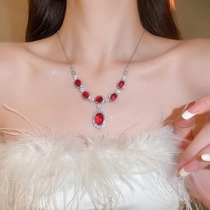 Close-up of elegant silver necklace with red oval gemstones and sparkling cubic zirconia