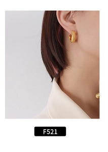 Detailed close-up of a gold-plated textured hoop earring worn by a model, style F521
