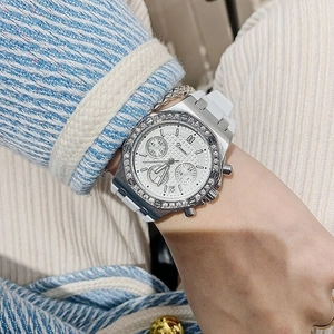 Close-up of chronograph watch with diamond bezel and white silicone strap on wrist