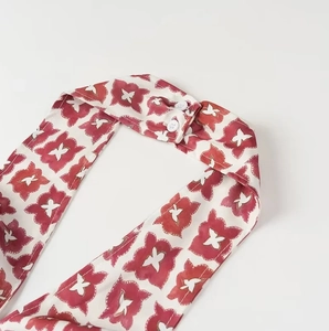 Detail of red floral halter neck with two white resin buttons on fabric
