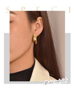 Detail of gold ribbon wave earrings showing brushed metal texture and modern origami design