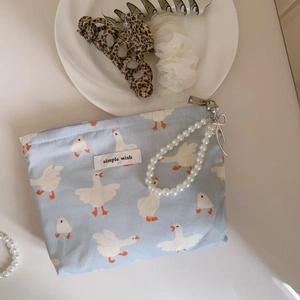 Detail of blue duck print fabric pouch with pearl chain strap and simple wish label