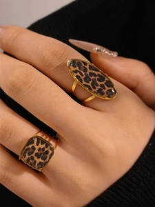 Close-up of golden oval and square leopard print rings worn on a hand with detail