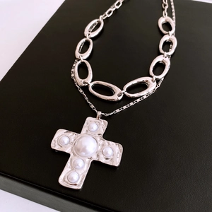 Detail of silver cross pendant with faux pearls and thick double chain design on black leather