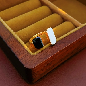 Detail shot of asymmetric black and white enamel geometric open ring on velvet