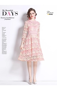 Détail d'une robe en dentelle rose montrant la broderie florale et le col montant chic