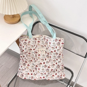 Detail of cute bear and apple print on white canvas tote bag with light blue handles