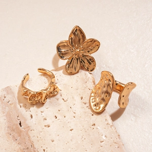 Detailed view of three gold adjustable rings with floral and hammered metal textures