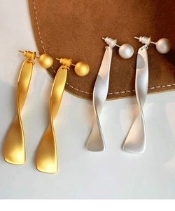 Detail view of twisted matte metal drop earrings in gold and silver finish