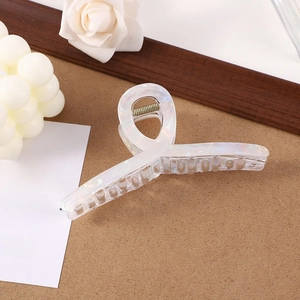 Iridescent candy stripe claw clip with pearl finish on a minimalist cork background