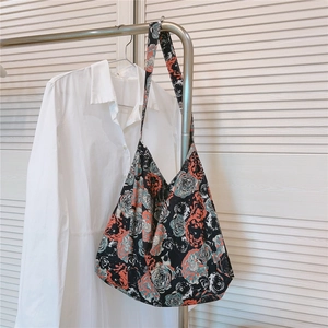 Detail of vintage floral cotton shoulder bag with large rose pattern hanging on a rack