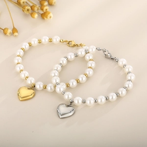 Détail de bracelets en perles or et argent avec pendentifs cœur et fermoirs mousqueton