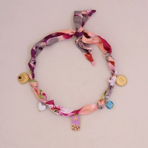Close-up of fabric strap bracelet with colorful pattern and golden celestial charms