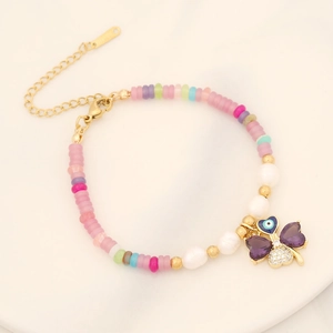 Detail of beaded necklace with purple butterfly, blue eye charm and pearl accents