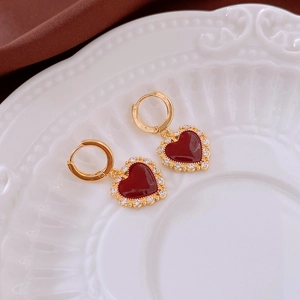 Detailed view of gold-plated heart earrings with red enamel and sparkling zircons