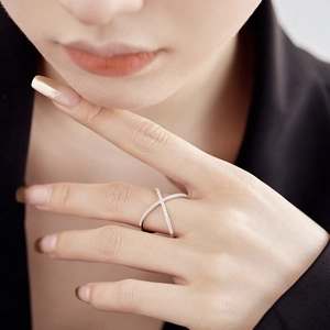 Gros plan d'une bague croisée en argent sertie de pierres portée par un mannequin chic