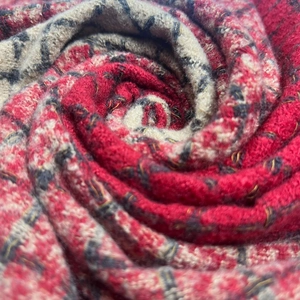 Macro view of spiral-wrapped color-block knit scarf showing red and grey wool texture