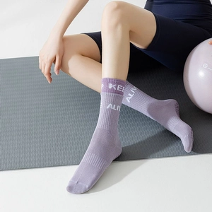 Purple knitted yoga socks with white text, worn by a model on a fitness mat