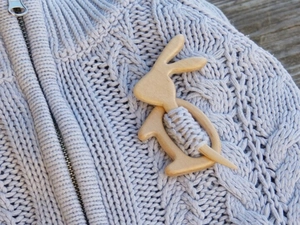 Close-up of wooden rabbit brooch pinned on light purple knit sweater for clothing detail