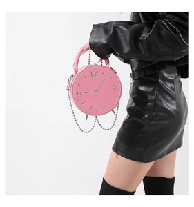Detailed view of pink clock-shaped handbag with silver metal dial and punk style chain trim