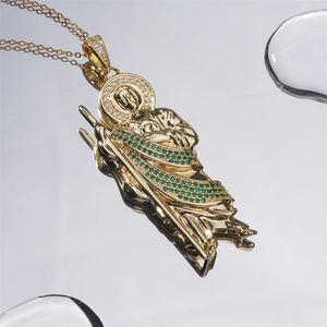 Golden St. Jude pendant necklace with green and clear zircon stones on mirror surface