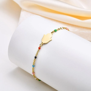 Detail of gold Fatima hand bracelet with colorful enamel beads on silk background