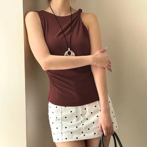 Detailed close-up of dark red sleeveless top with elegant asymmetric pleated neckline texture
