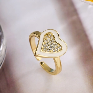 Macro shot of adjustable gold heart ring with pavé zircons and white enamel border