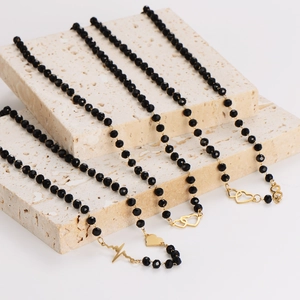 Elegant black glass beaded necklaces with gold heartbeat and heart pendants on stone