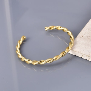 Detailed close-up of a golden twisted rope cuff bracelet with a polished open design