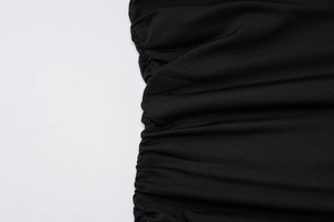 Detail of ruched side seams and high-stretch fabric texture on a black slim fit T-shirt