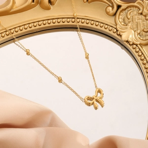 Bracelet élégant en acier titane doré avec pendentif nœud et chaîne à perles satellite
