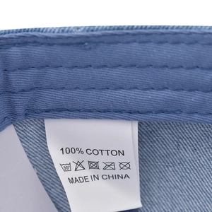 Close-up of internal washing label showing 100% cotton fabric on denim baseball cap