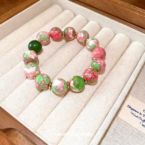 Elegant gold-plated bracelet featuring green and pink floral gradient glass beads